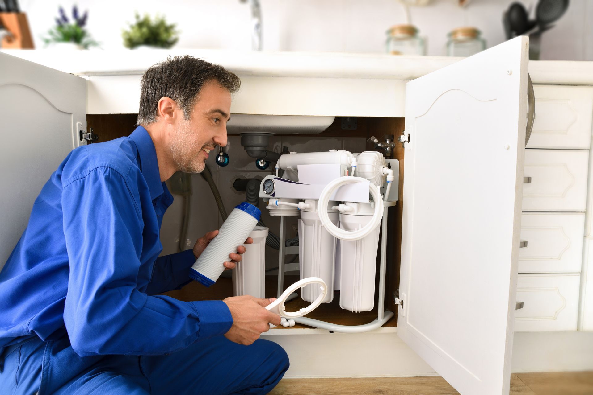Technician installing reverse osmosis equipment under the sink. Technician installing reverse osmosis equipment under the sink.