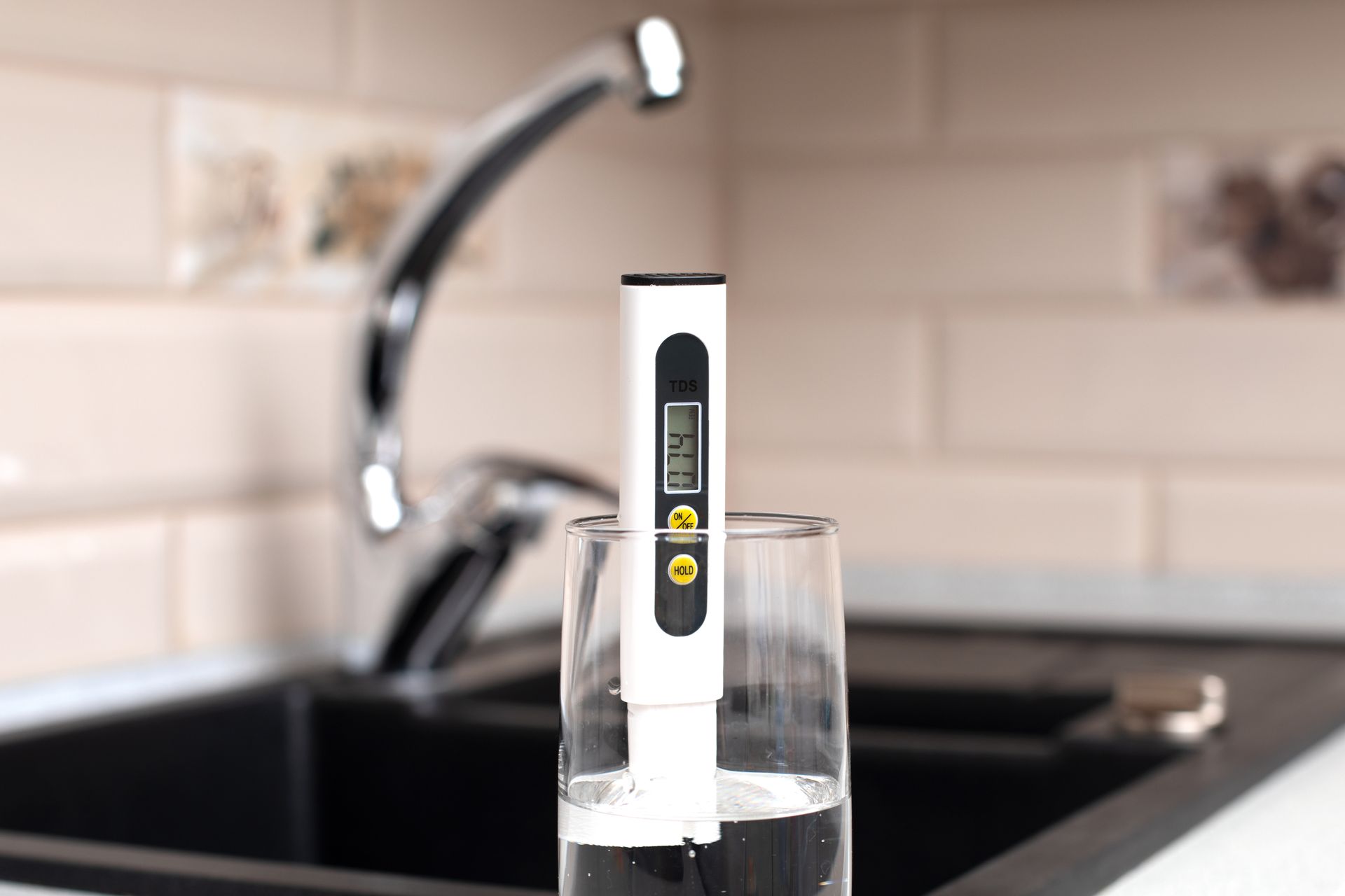 Digital pH meter in a glass of water on a kitchen sink counter Digital pH meter in a glass of water on a kitchen sink counter