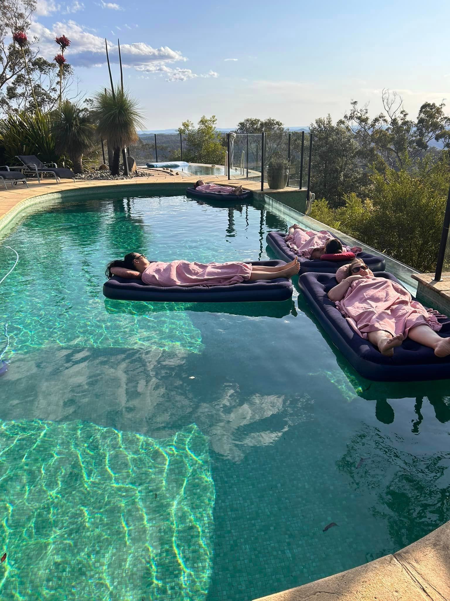 A group of people are laying on rafts in a swimming pool.
