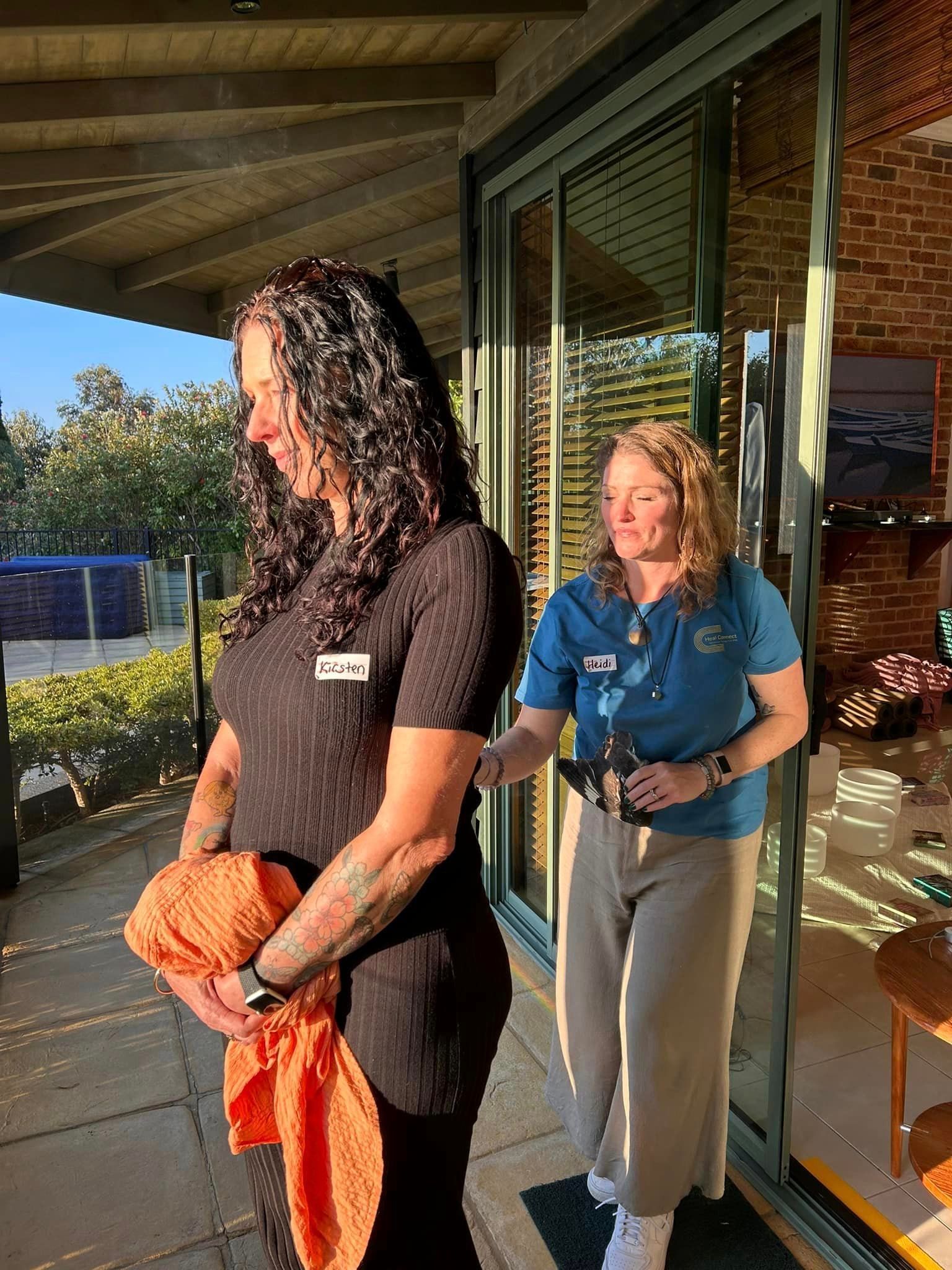 Two women are standing next to each other on a porch.