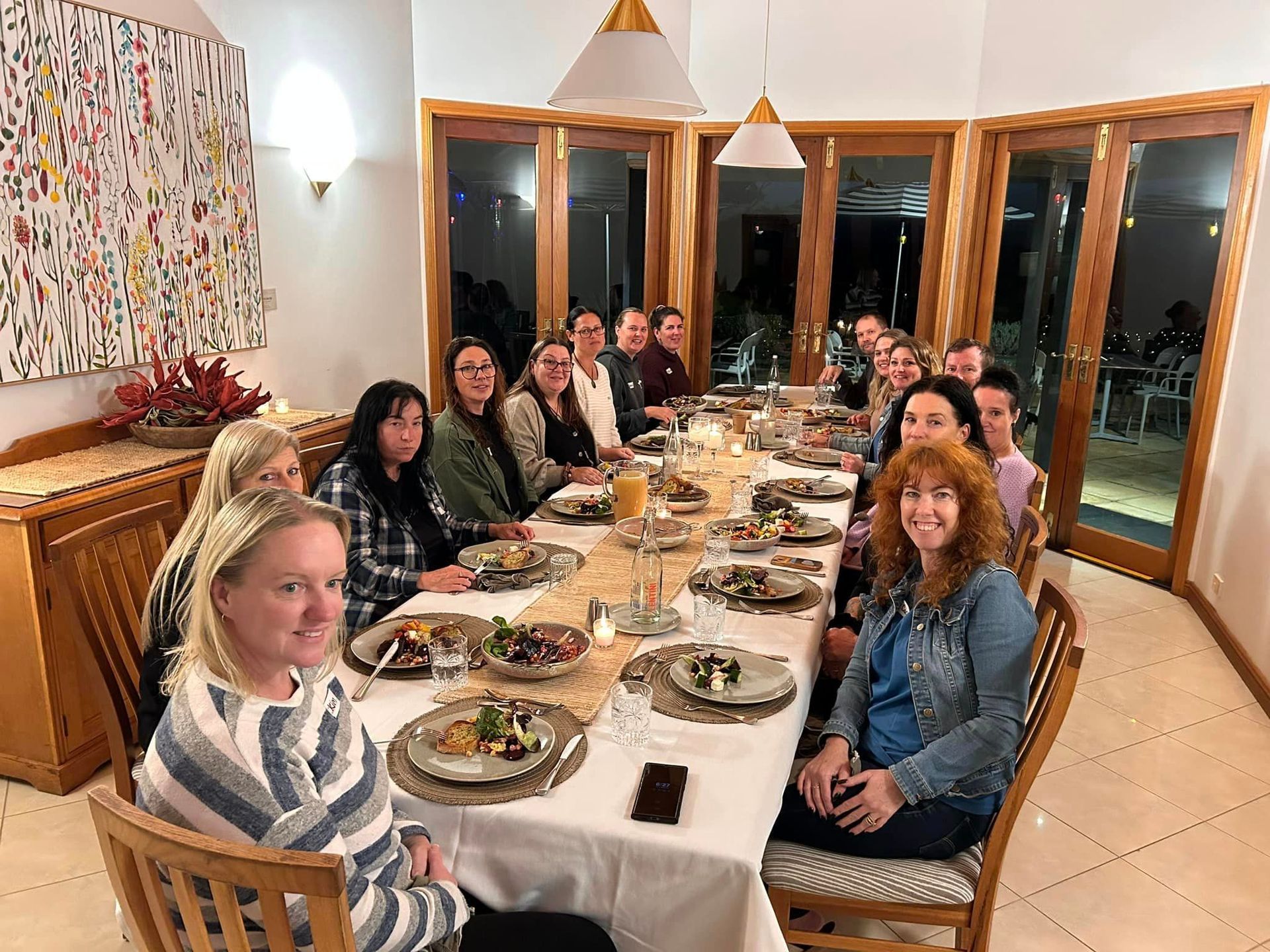 A group of people are sitting at a long table with plates of food.