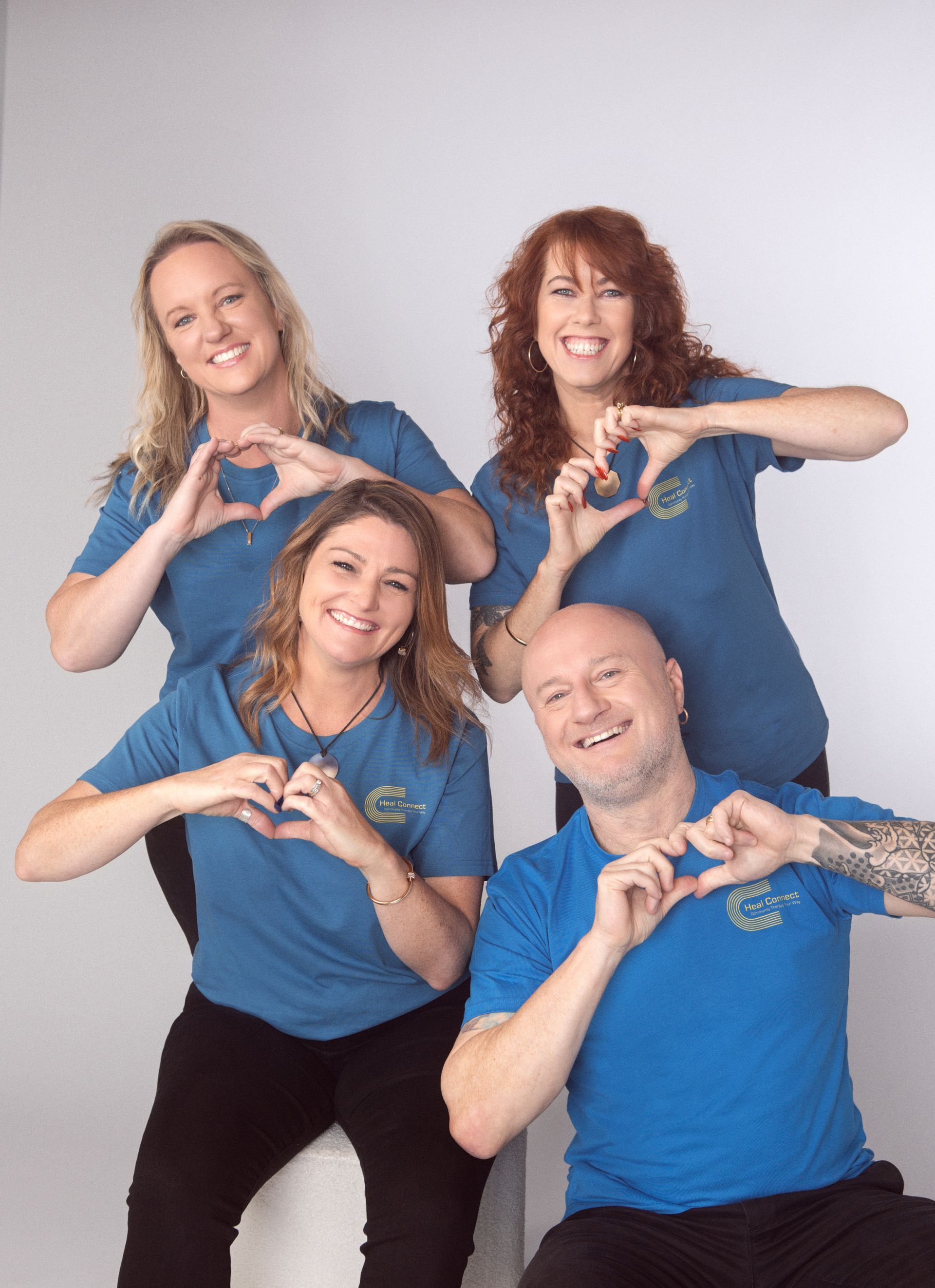 A Woman Wearing A Denim Jacket And A White Dress Is Leaning Against A Railing And Smiling — Heal Connect in Long Jetty, NSW