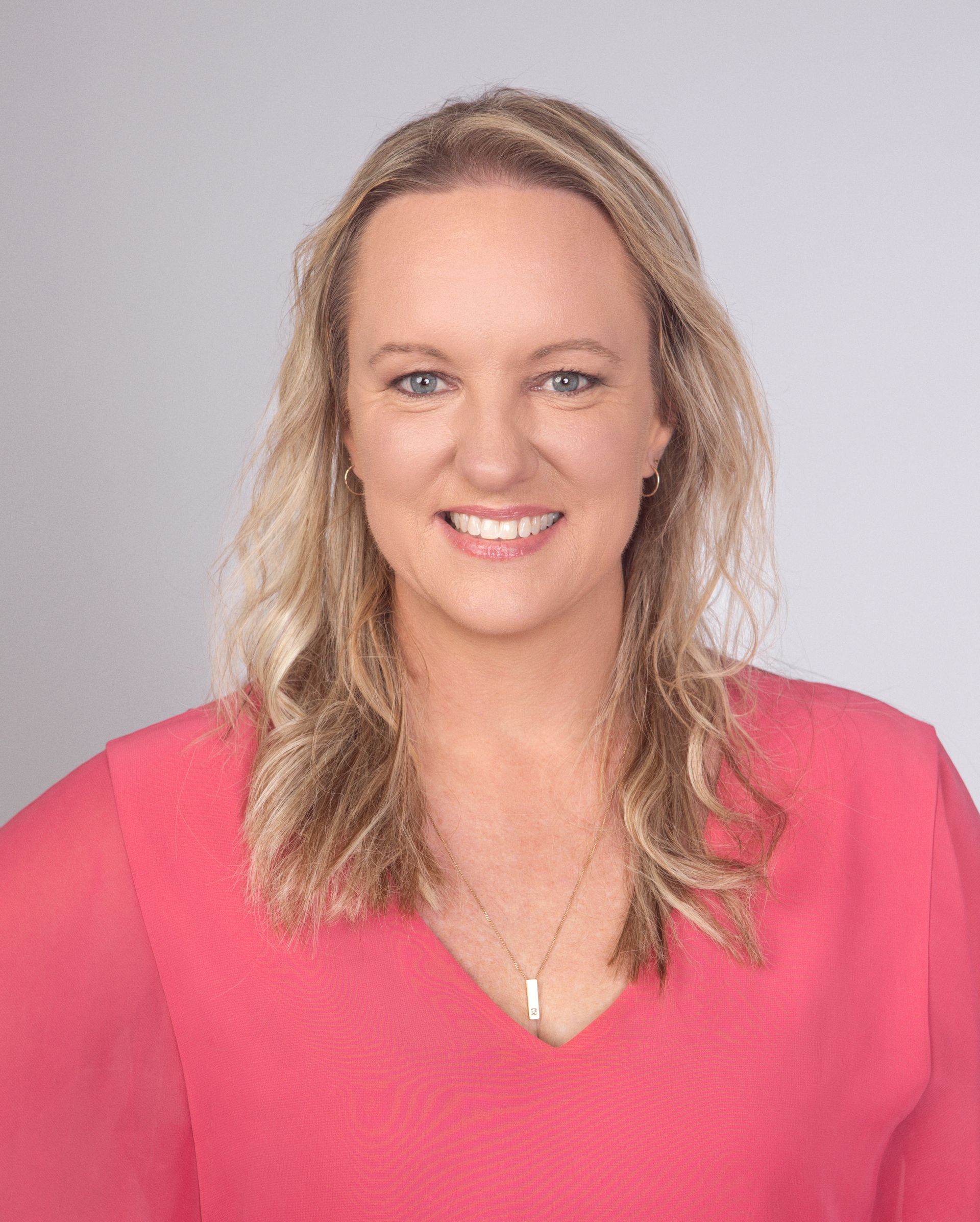 A Woman In A Blue Shirt Is Smiling In Front Of A Sign That Says World Class Training — Heal Connect in Long Jetty, NSW