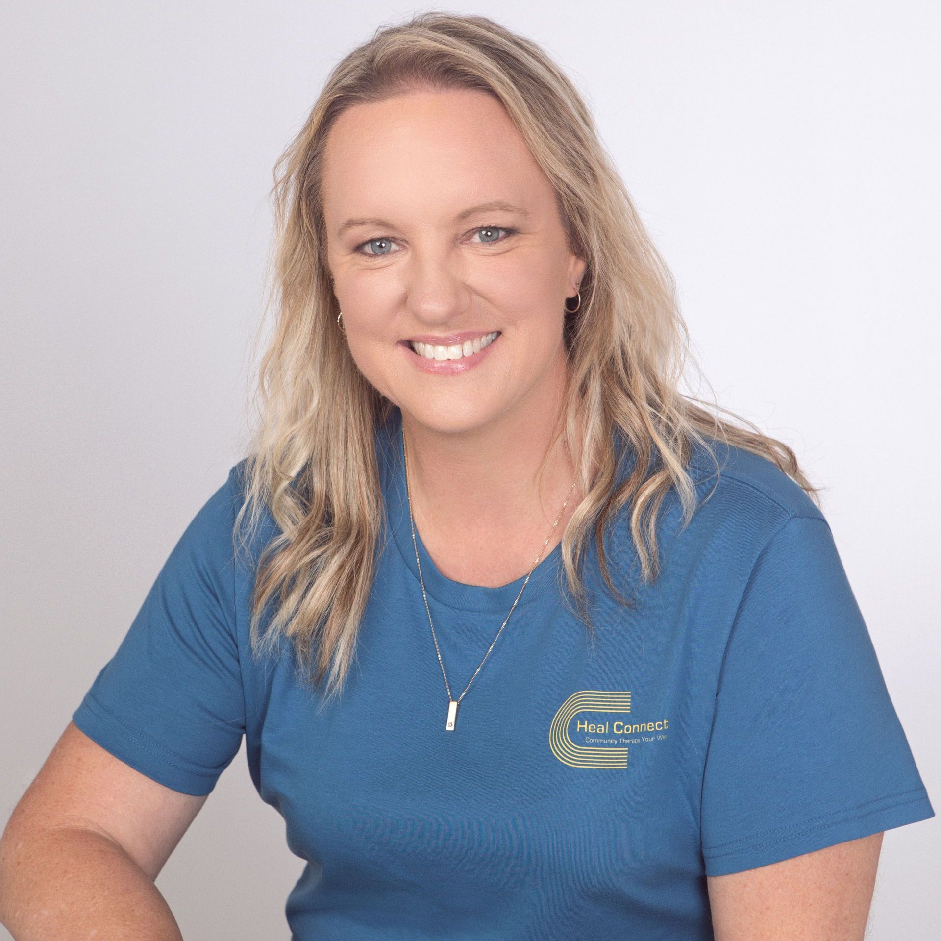 A woman wearing a blue shirt is smiling for the camera