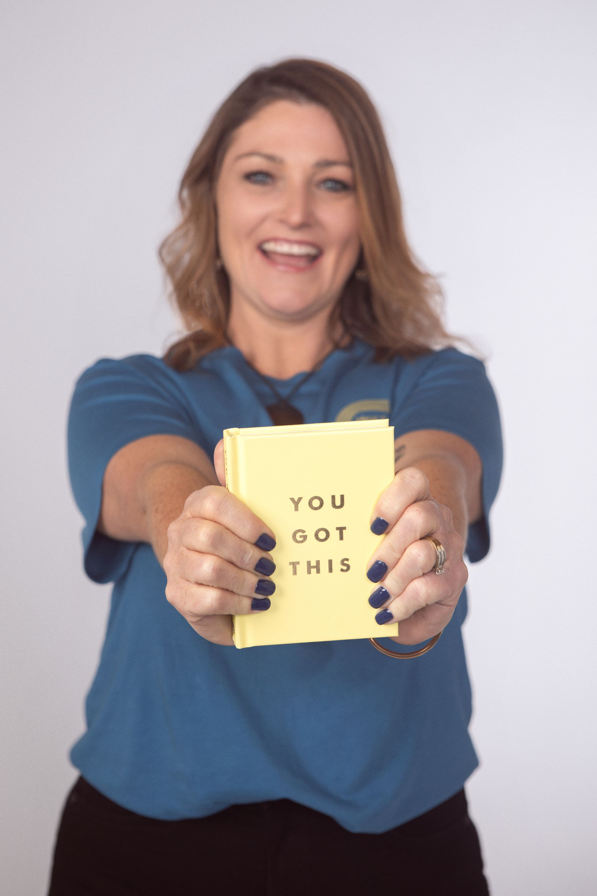 A Woman With Red Hair And Tattoos Is Sitting On A Bench And Smiling — Heal Connect in Long Jetty, NSW