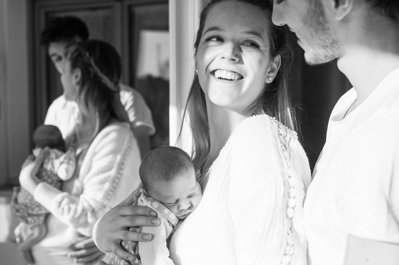 Eine Frau lächelt und hält ein schlafendes Baby im Arm;