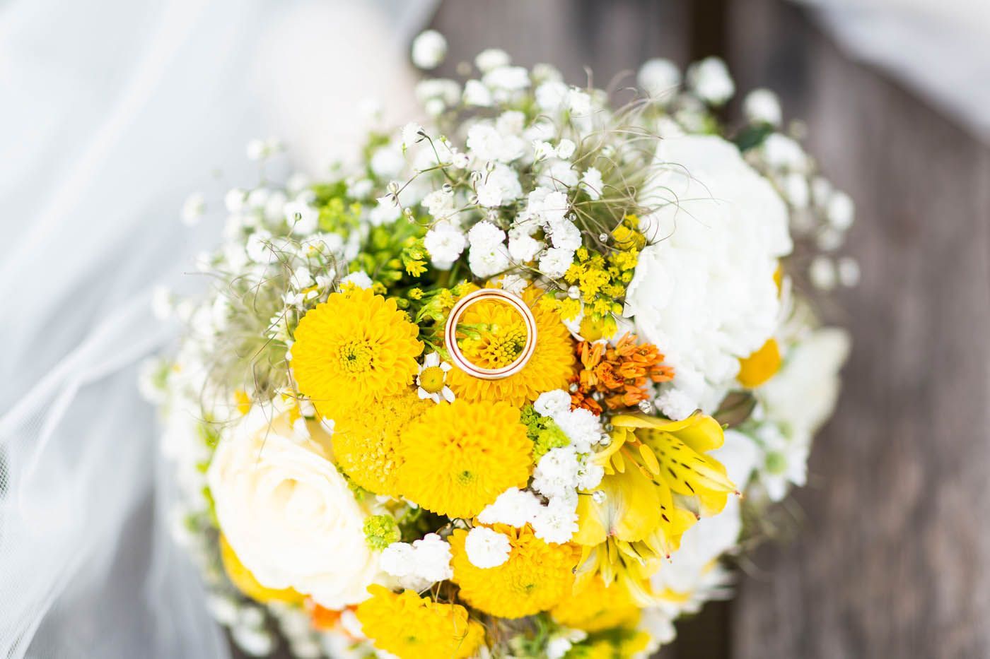 Brautstrauß mit gelben und weißen Blumen, Ehering.