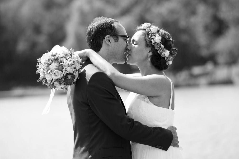 Das frischvermählte Paar küsst sich im Freien und hält einen Brautstrauß