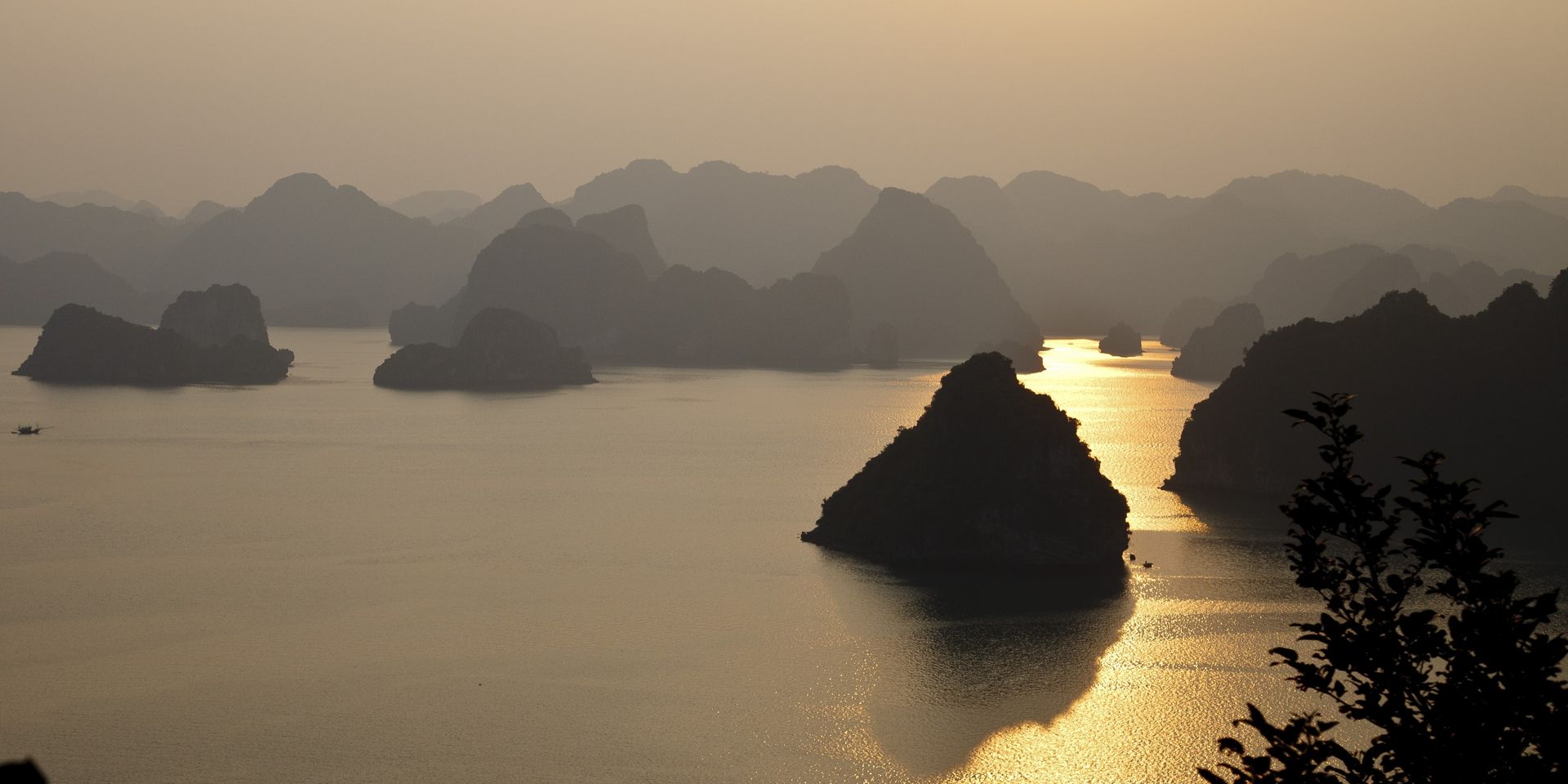 Dunstige Meereslandschaft mit Kalksteinkarst und sonnenbeschienenem Wasser; möglicherweise Halong-Bucht, Vietnam.