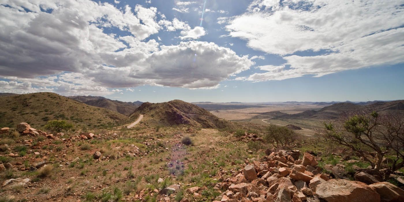 Mit Blick auf eine zerklüftete, hügelige Landschaft unter einem hellen, leicht bewölkten Himmel.