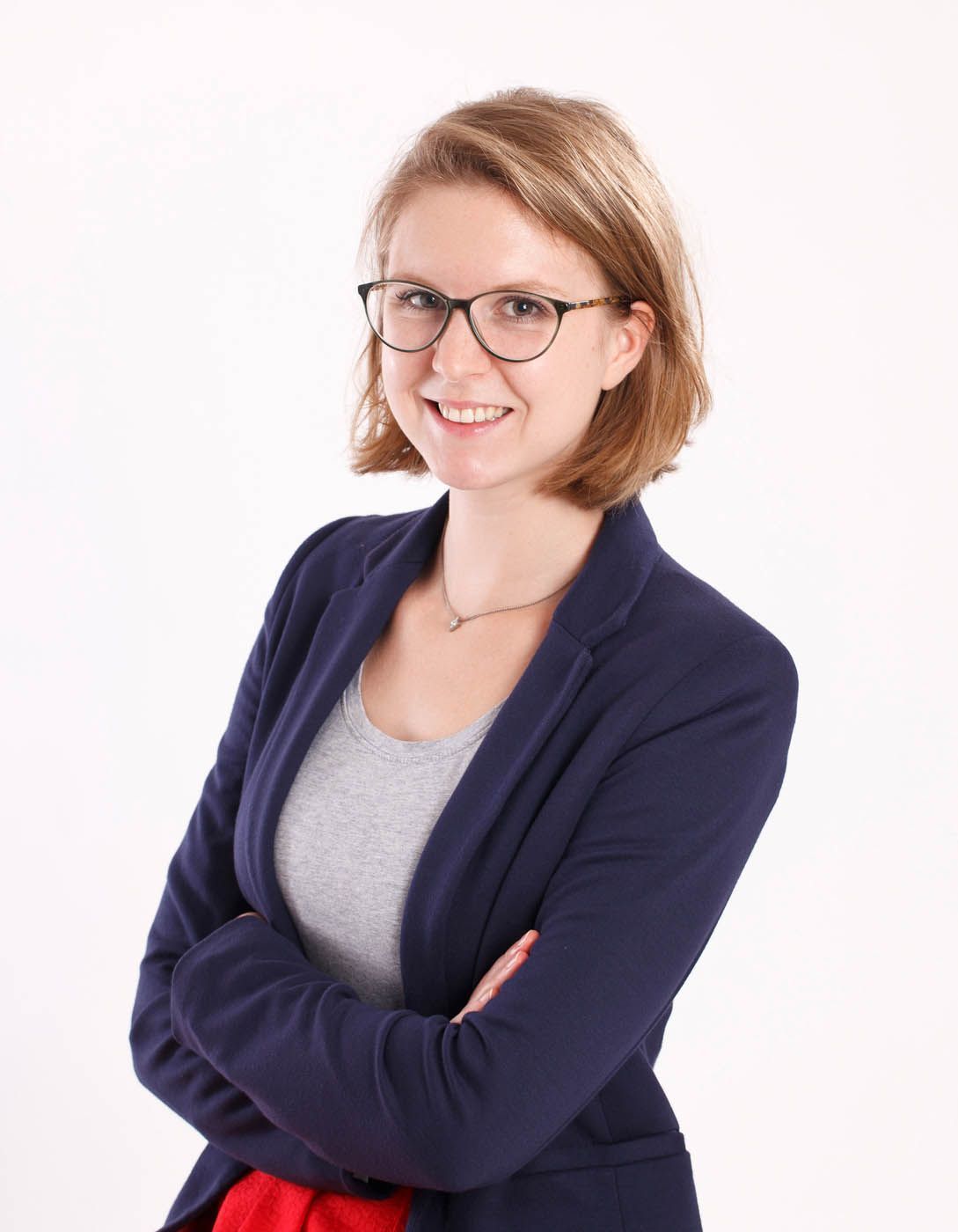 Frau mit Brille und verschränkten Armen mit dunkelblauem Blazer