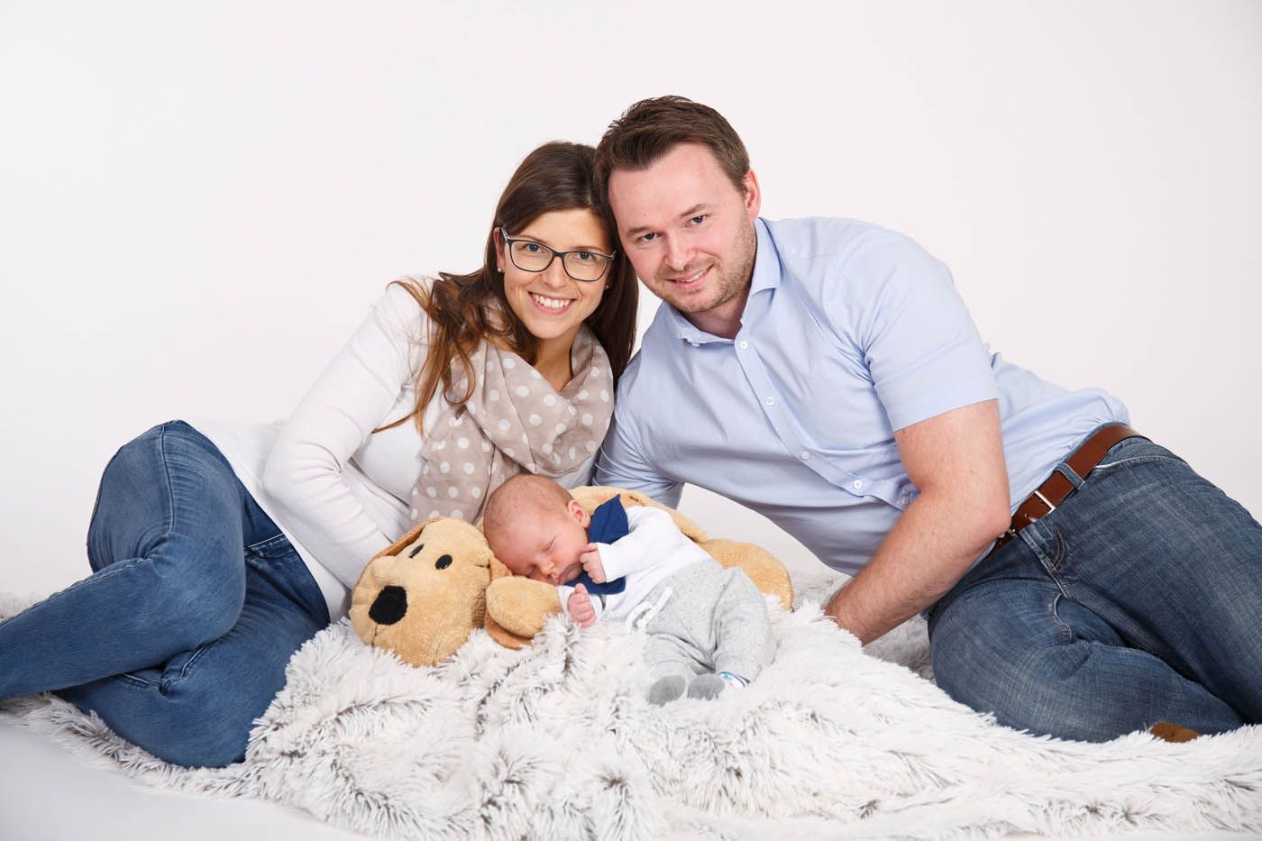 Die Eltern lächeln und wiegen ihr Neugeborenes in einer flauschigen Decke