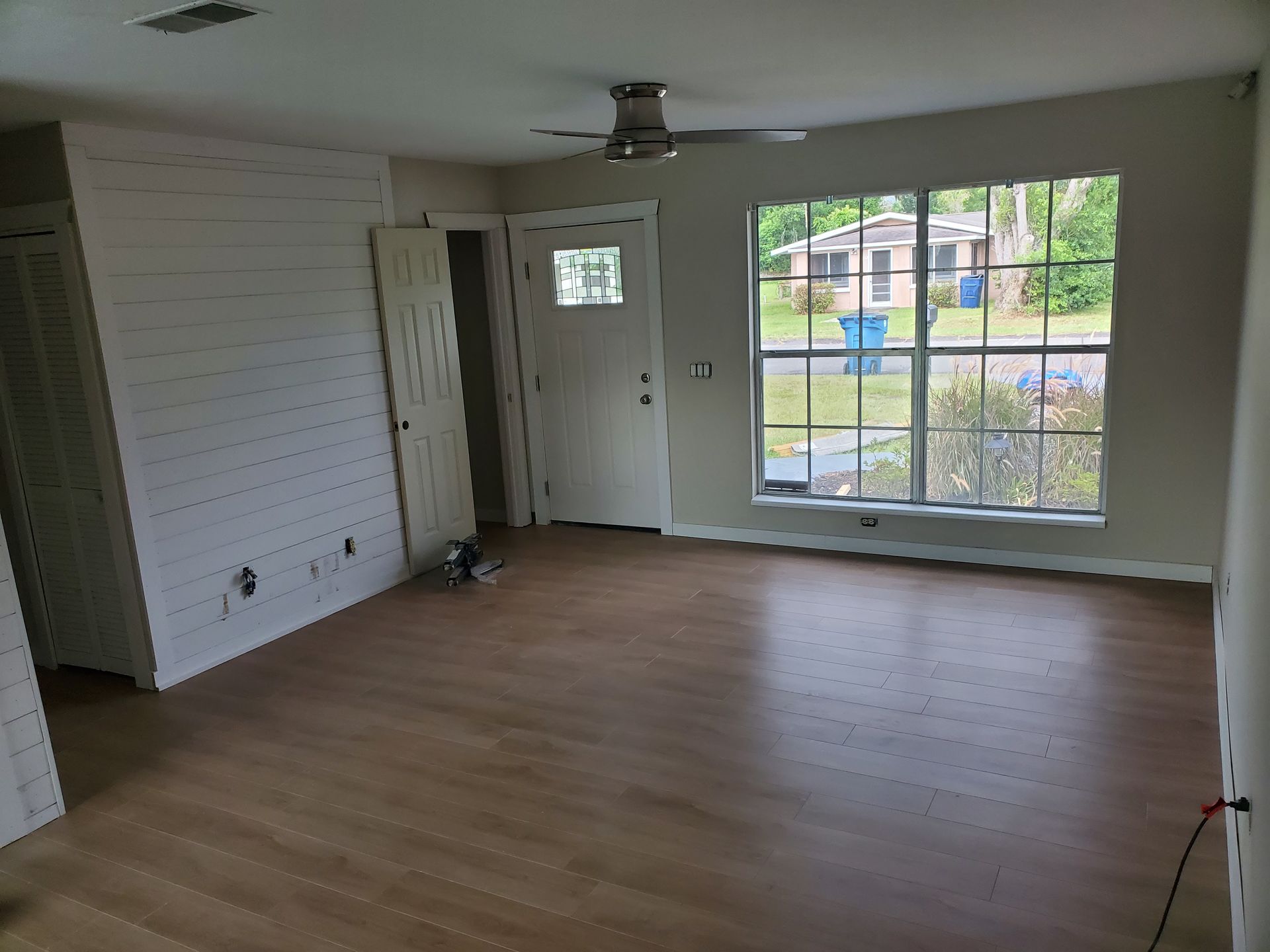 An empty living room with hardwood floors and a ceiling fan.