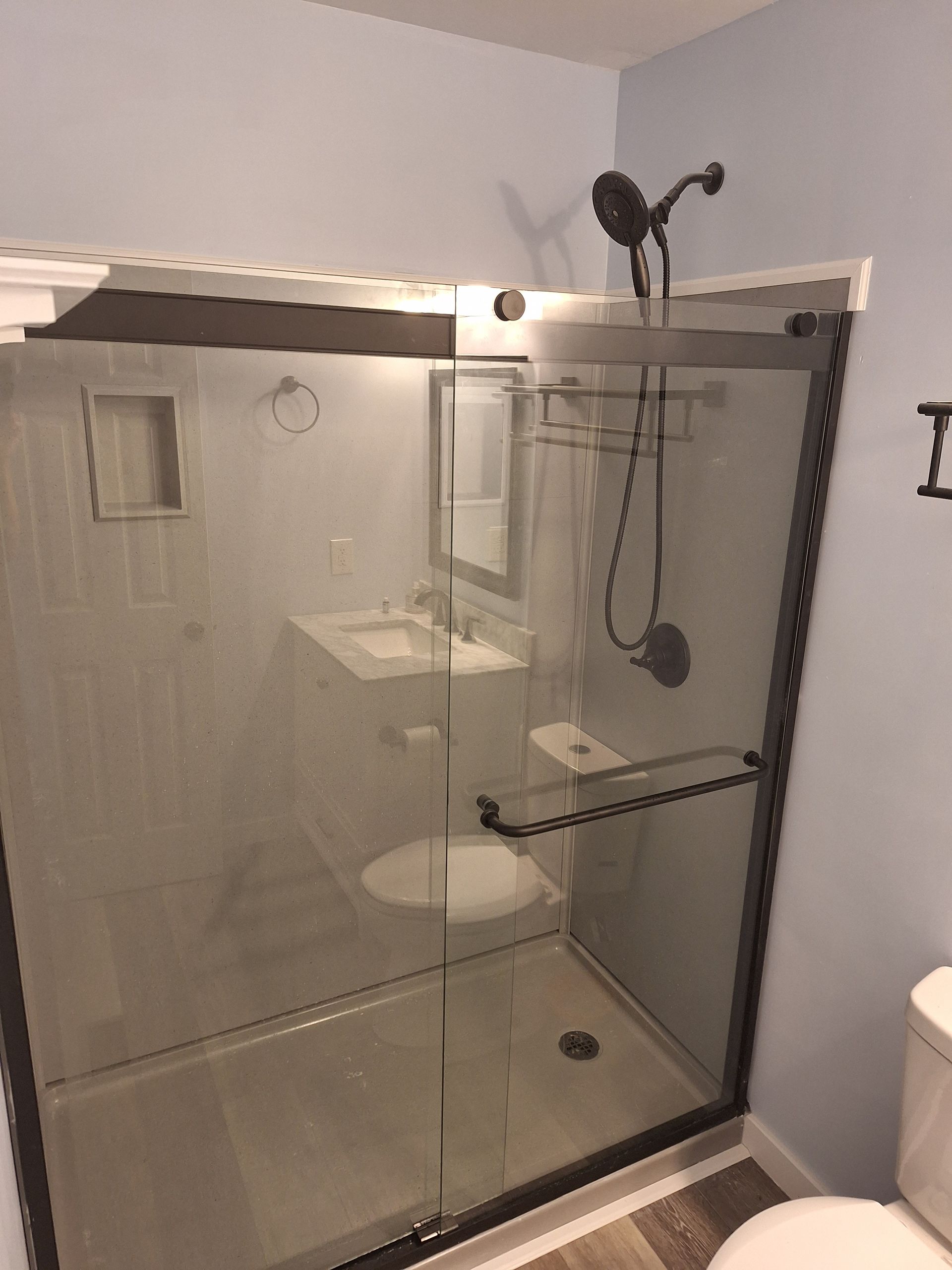 A bathroom with a walk in shower , sink , toilet and mirror.