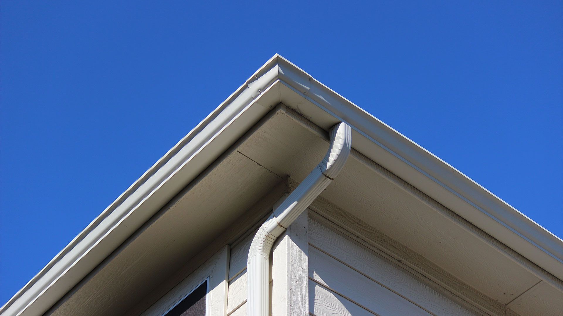 Looking up at the roof of a house with a blue sky in the background
