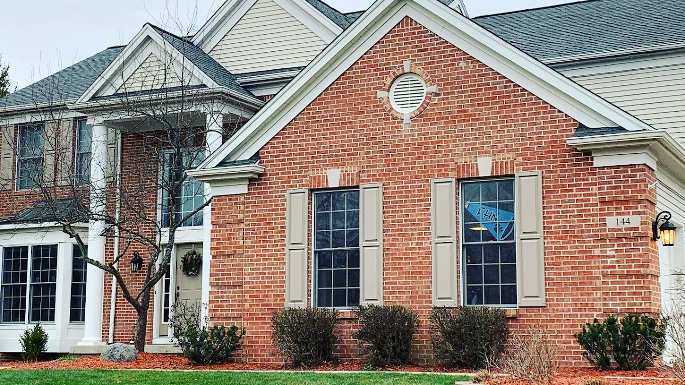 A large brick house with a gray roof and white trim.
