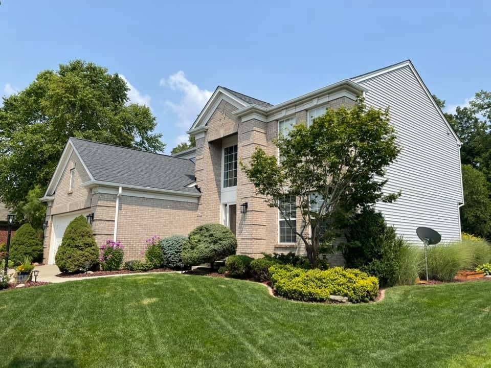 A large brick house with a lush green lawn in front of it.