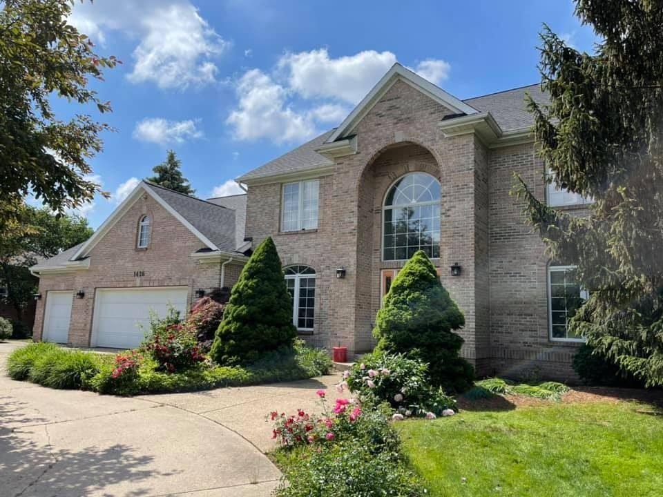 A large brick house with a driveway and trees in front of it