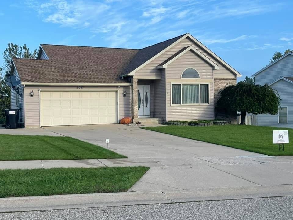 A house with a garage and a sign in front of it