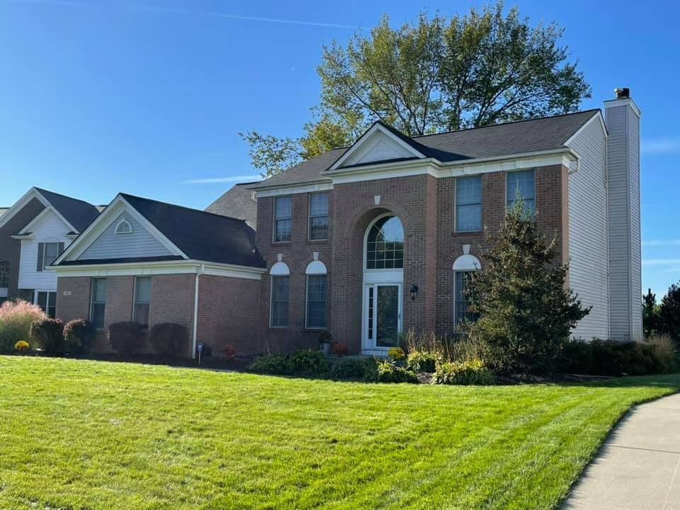 A large brick house with a lush green lawn in front of it