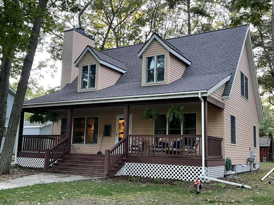 A large house with a large porch and a gray roof.