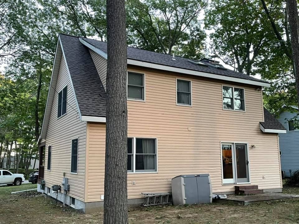 The back of a house with a tree in front of it.