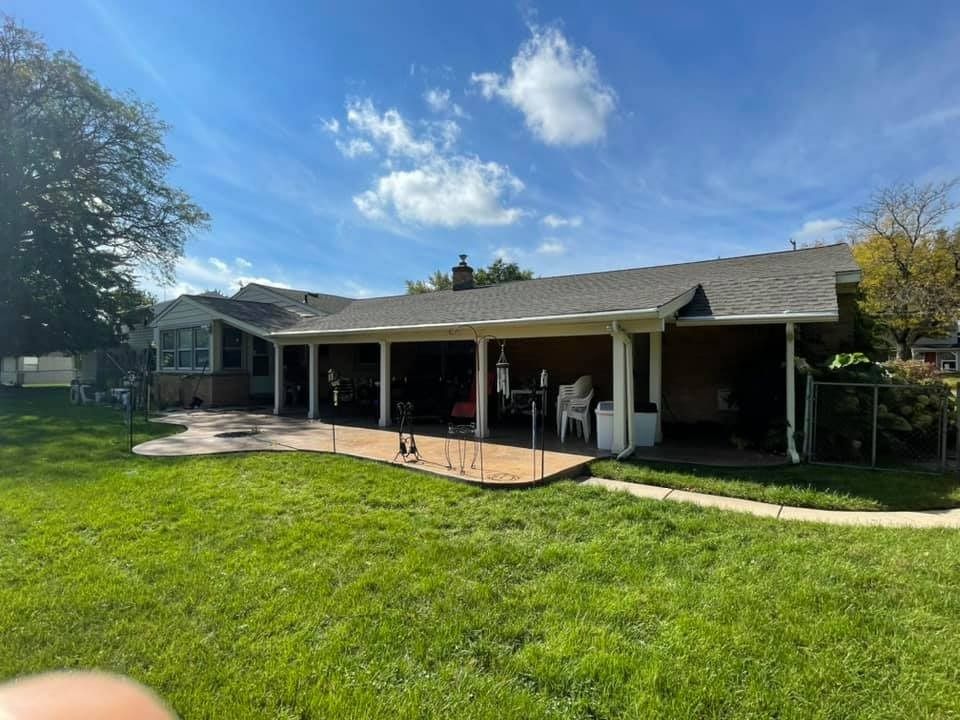 A house with a large covered porch and a large lawn in front of it.