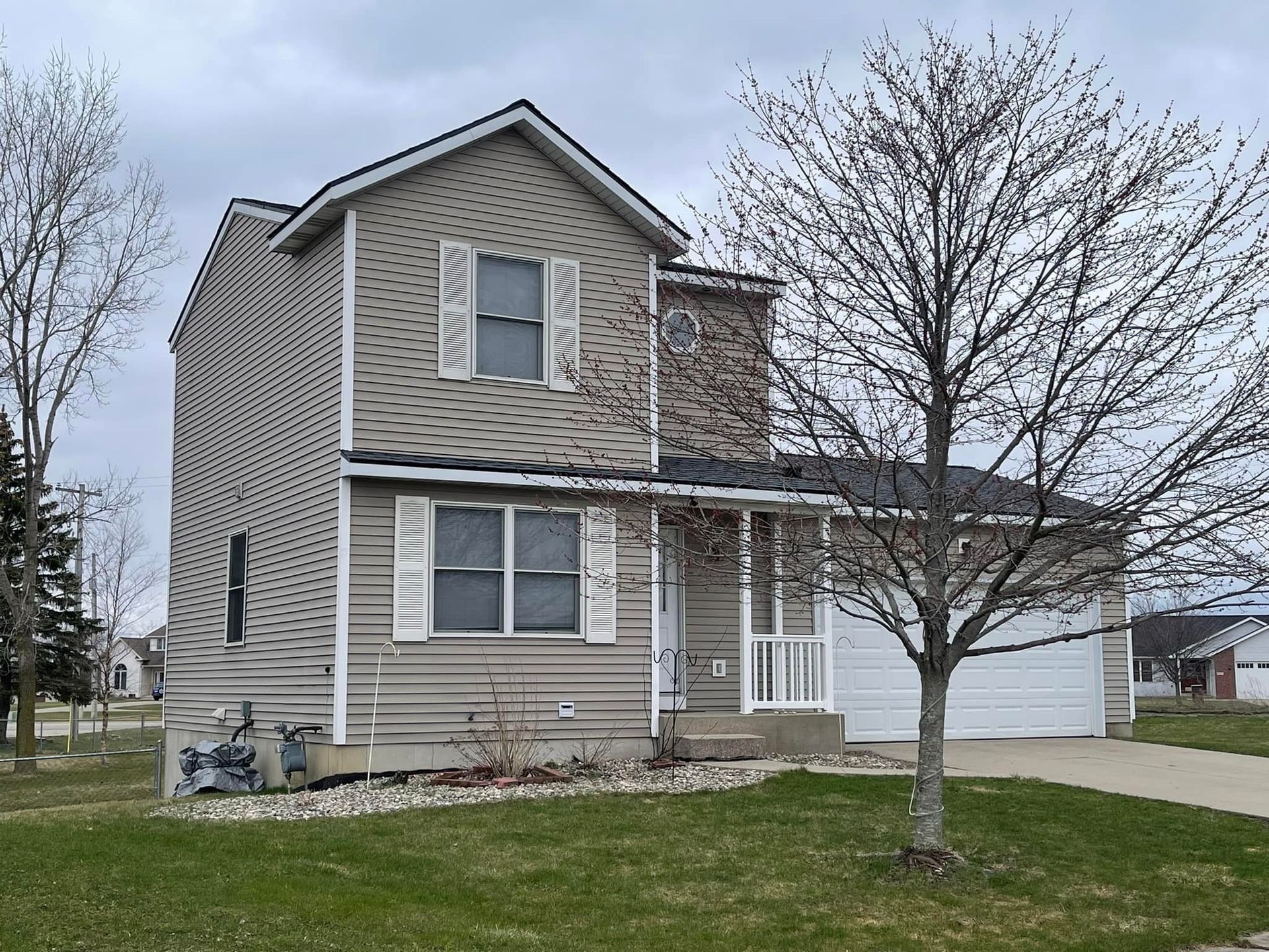 A house with a garage and a tree in front of it.