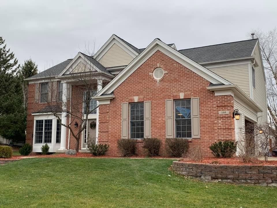 A large brick house with a large lawn in front of it