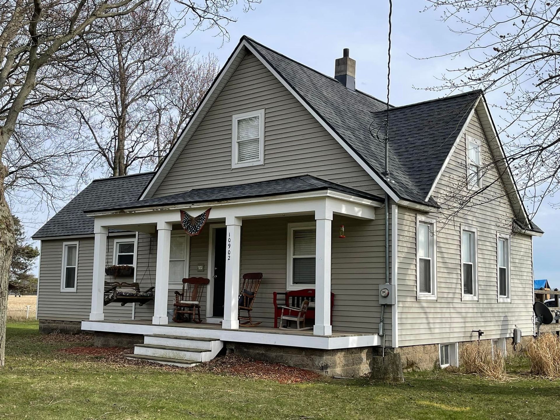 A large house with a porch and chairs on it.