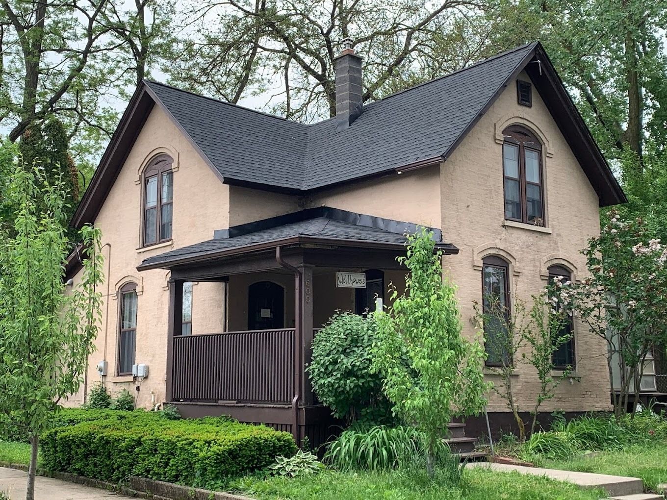 A tan house with a black roof and a porch