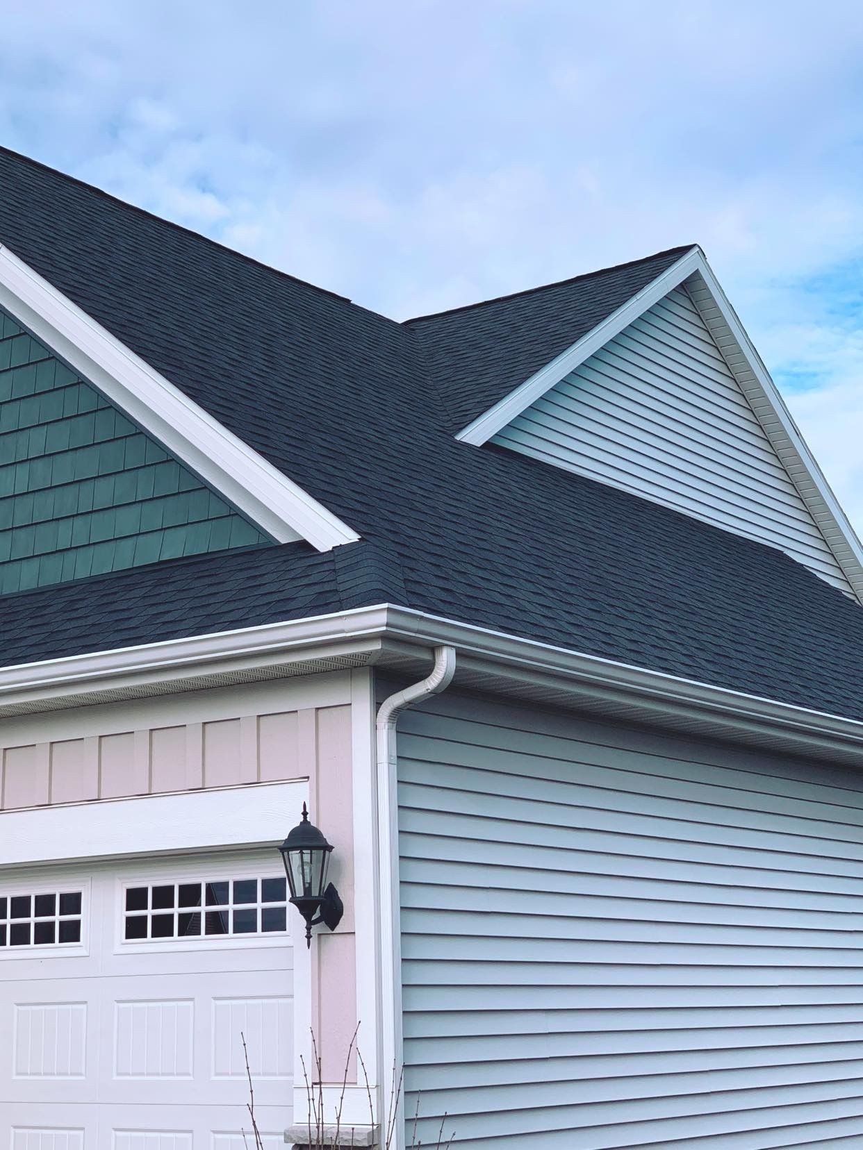 A house with a black roof and a pink garage door.