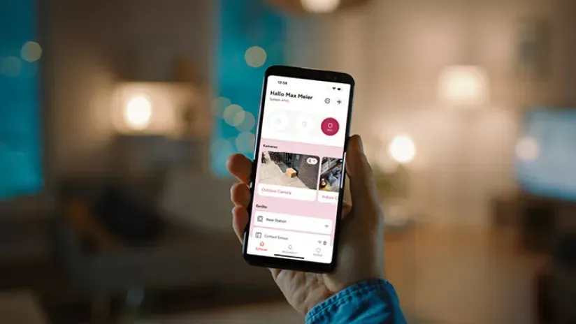 Hand hält Telefon mit leerem Bildschirm neben einem Laptop mit leerem Bildschirm.