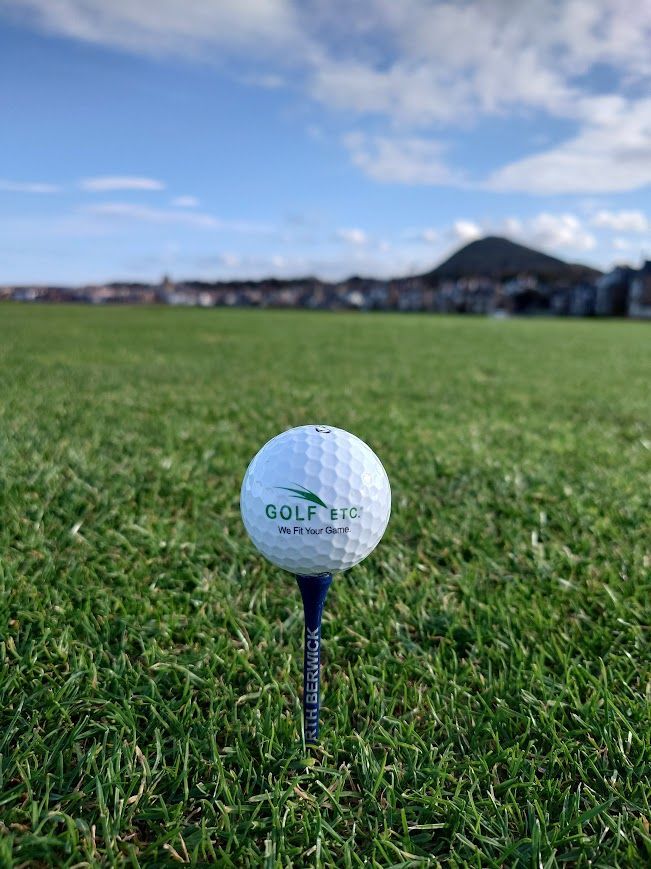 Een golfbal op groen gras, met een wazige achtergrond van een golfbaan.