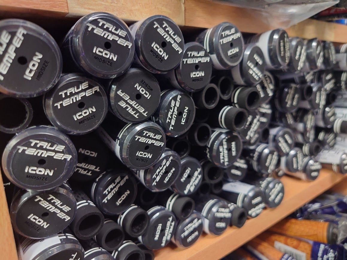 Zes mannen in golfkleding staan ​​op een golfbaan, met hun clubs in de hand. Zonnige dag, bomen op de achtergrond.