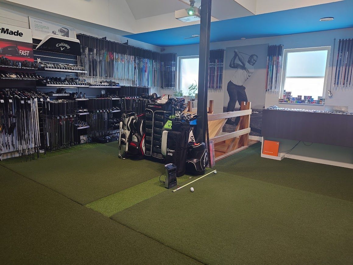 Zes mannen in golfkleding staan ​​op een green, met hun clubs in de hand. Het is een zonnige dag.