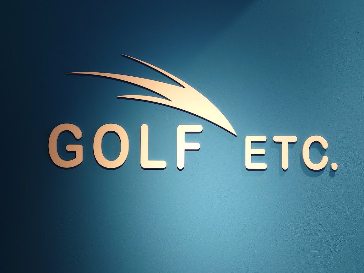 Een golfclub slaat een golfbal, waardoor stof en gras op de groene, zonnige golfbaan in het rond vliegen.