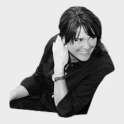 Vrouw in een zwart shirt, leunend, glimlachend, met haar hand op haar hoofd en naar rechts kijkend.