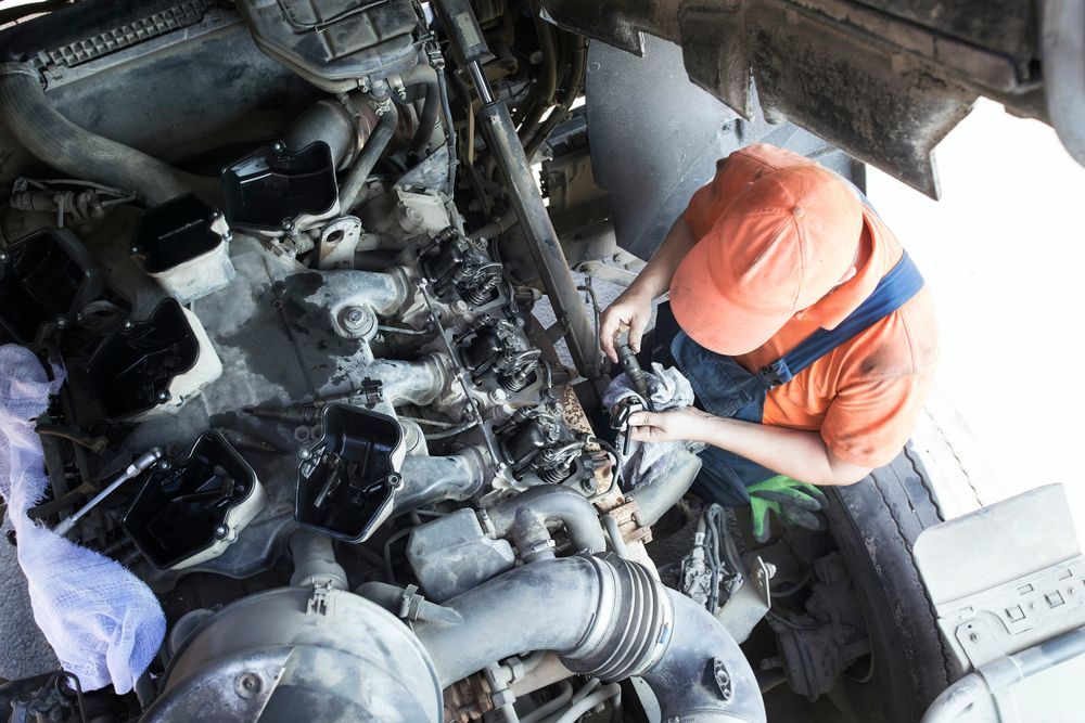 Worker in orange jacket inspecting machinery inside an industrial engine compartment.