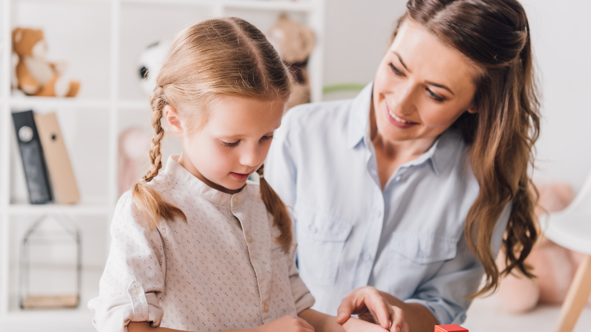 A young boy with down syndrome is sitting at a table playing with colorful toys.