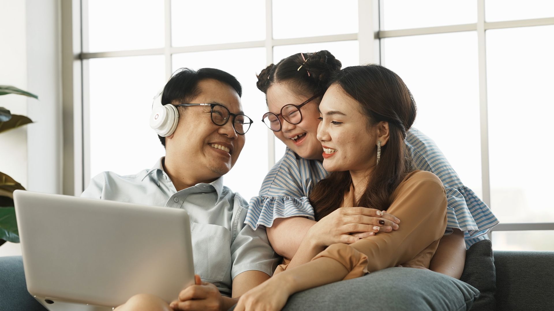 A family is sitting on a couch looking at a laptop.
