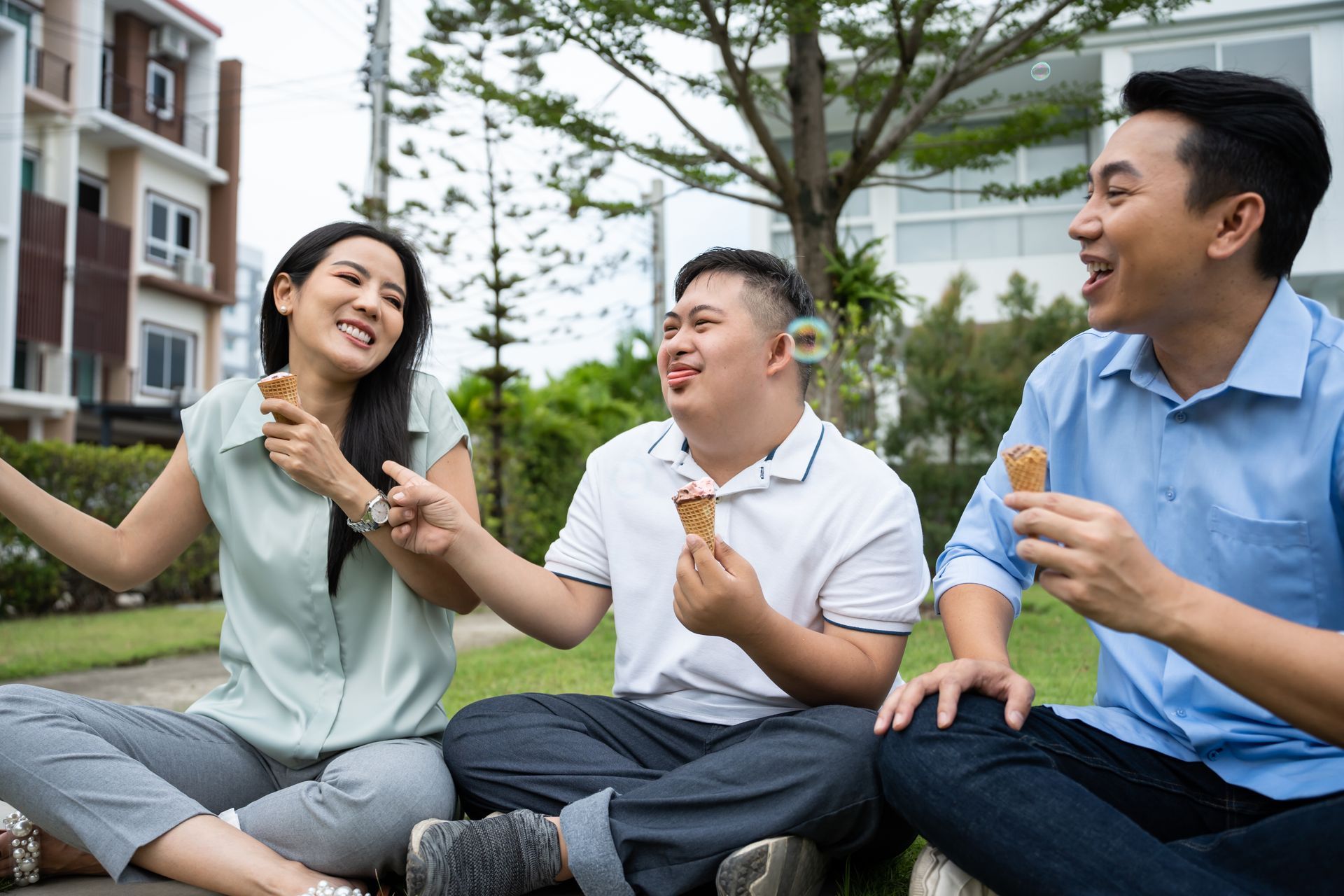 A group of people are sitting on the grass eating ice cream cones.