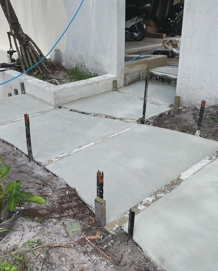 A concrete walkway is being built in front of a house