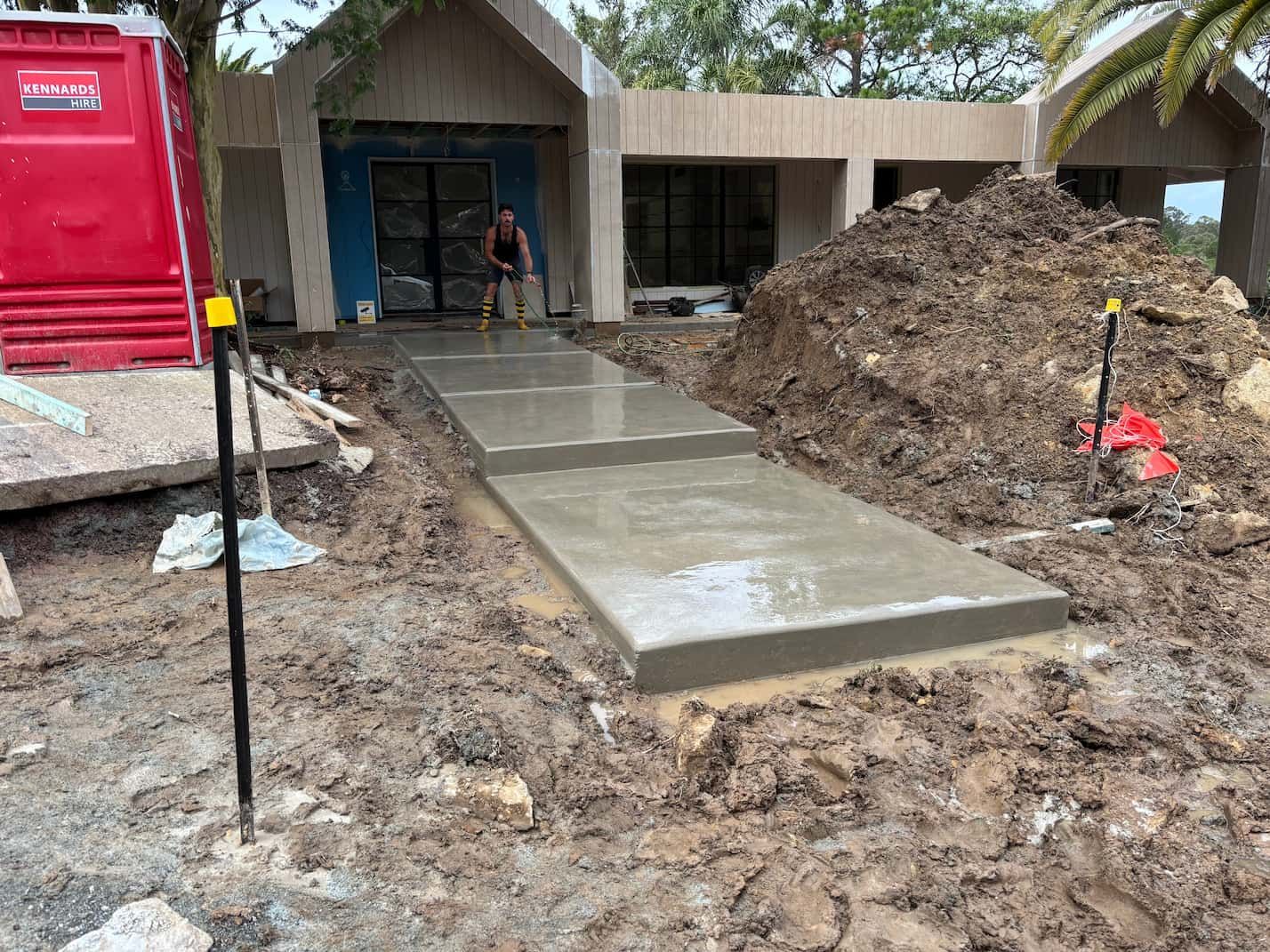 A concrete walkway is being built in front of a house.