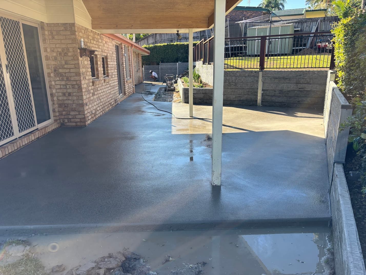 A concrete walkway is being built in front of a brick house.