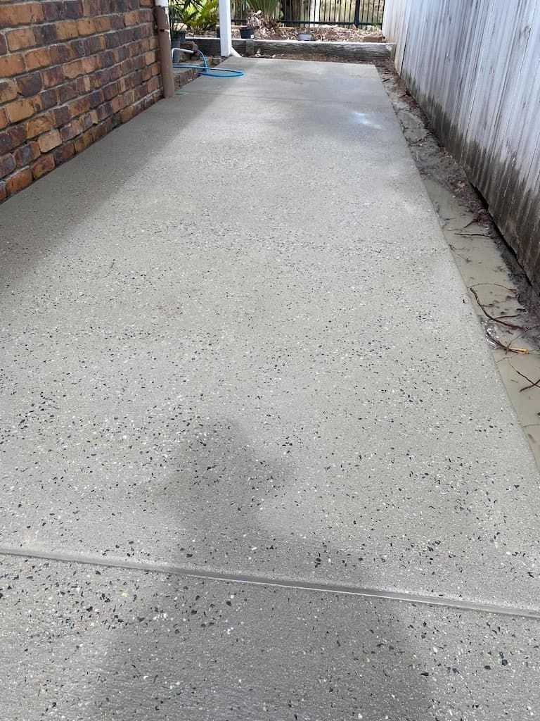 A concrete walkway with a brick wall in the background.