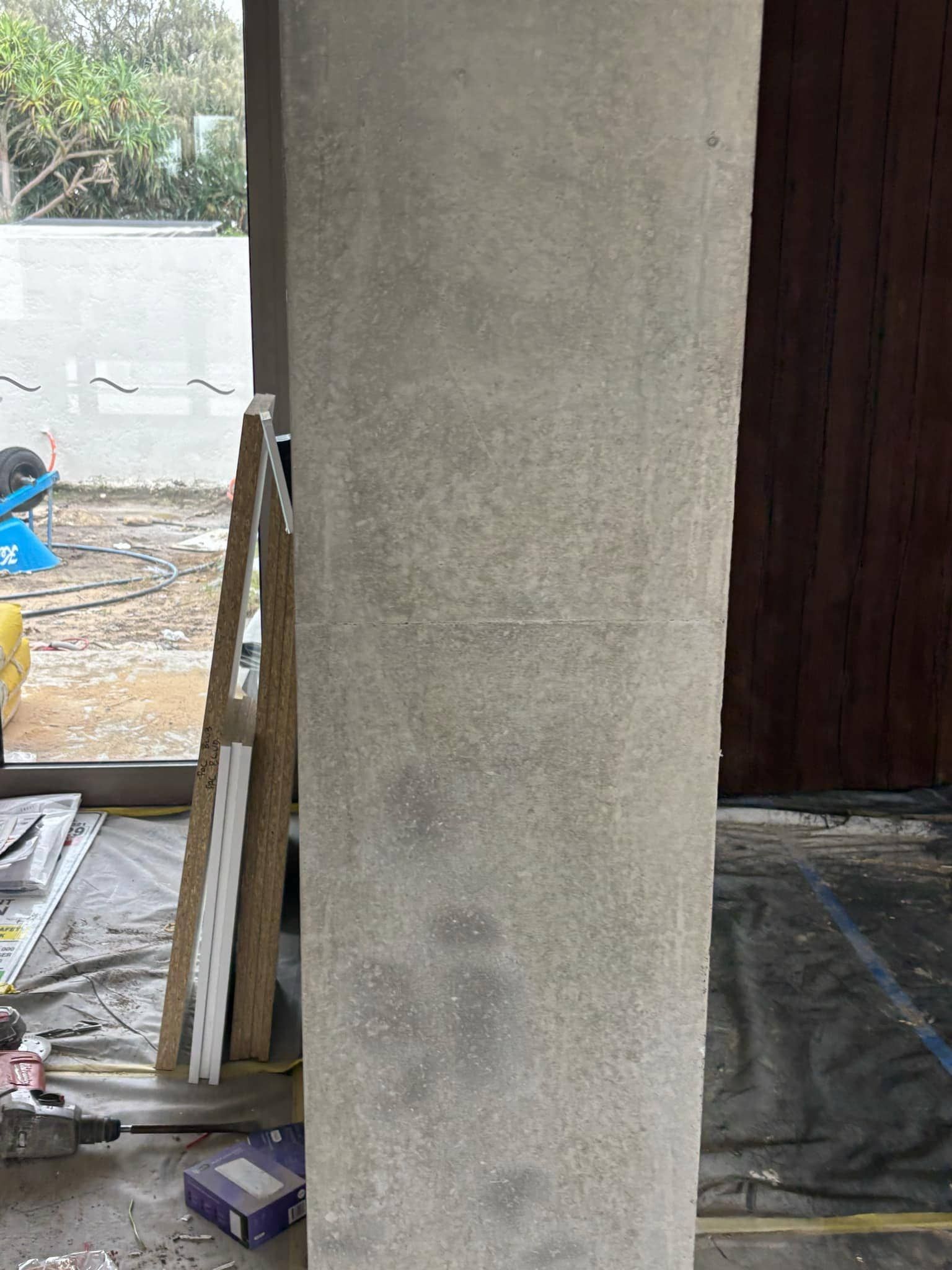 A concrete column is sitting in a room next to a window.
