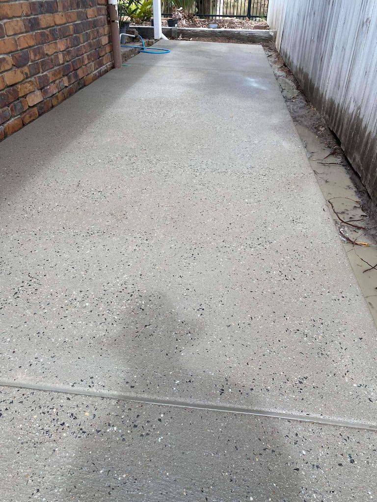 A concrete walkway with a brick wall in the background.