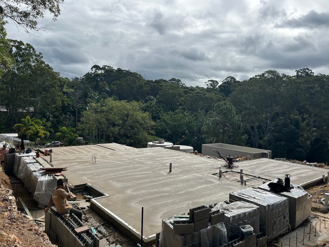 A construction site with a lot of concrete and trees in the background.