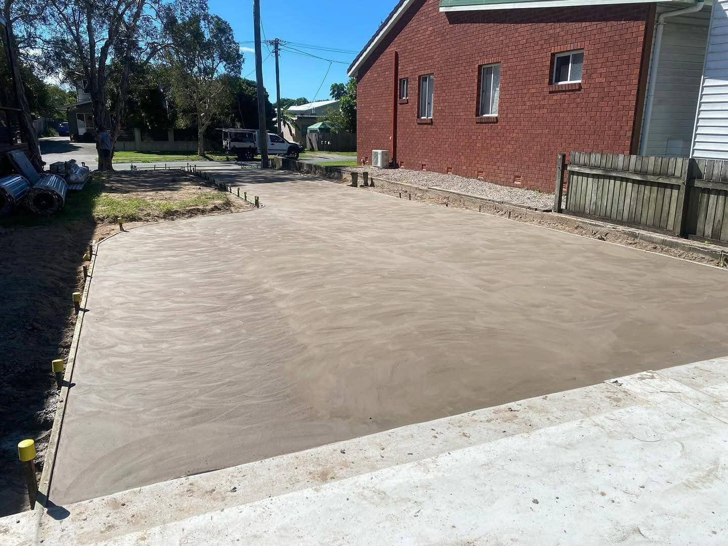 A concrete driveway is being built in front of a brick house.